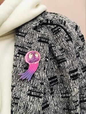 Laissez-vous envoûter par cette adorable broche méduse violet pailletée, un bijou unique qui allie douceur et éclat.