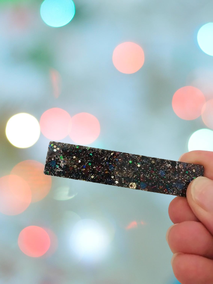 Ajoutez une touche de brillance à vos coiffures avec notre magnifique barrette en résine pailletée noire. Cet accessoire pour cheveux est à la fois chic et original