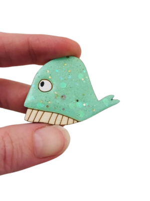Laissez-vous charmer par notre broche baleine verte pailletée, une pièce artisanale originale qui raconte une véritable histoire de famille