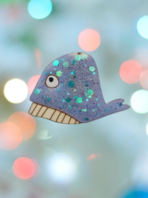 Plongez dans un océan de créativité avec notre broche baleine bleue pailletée, une pièce artisanale conçue avec amour et inspirée d’une histoire de famille.
