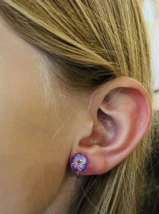 Clip d'oreille silicone fleur violette portée par une enfant